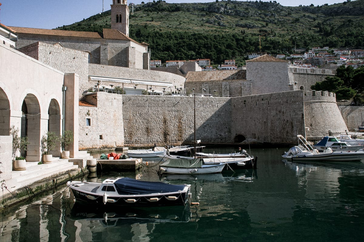 Small boats beside the stone walls of Dubrovnik's harbour.