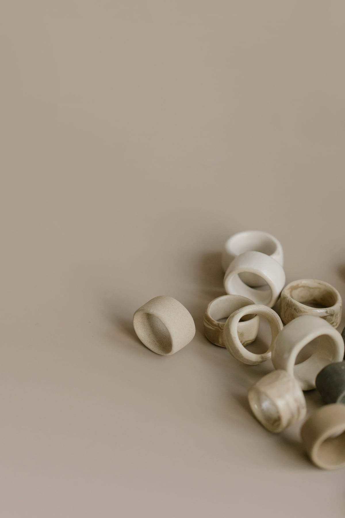 Cream ceramic rings gathered on a neutral surface with soft shadows.